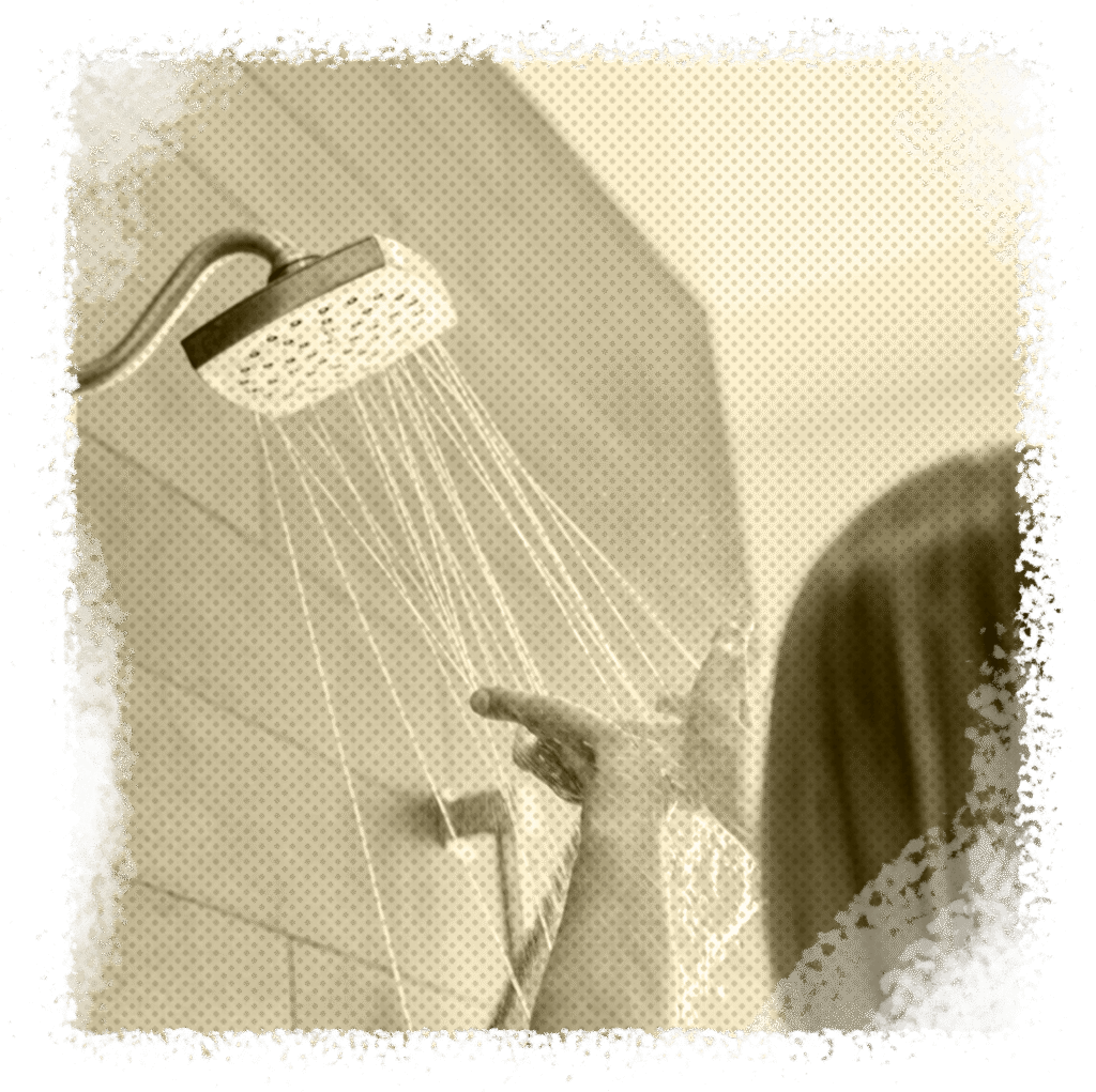 Person reaching for a showerhead with water flowing, illustrating the convenience of tankless water heaters for on-demand hot water in homes.