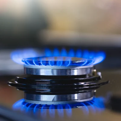 Close-up of a gas stove burner with blue flames, representing efficient gas appliance installation for kitchens and homes in Houston, TX.